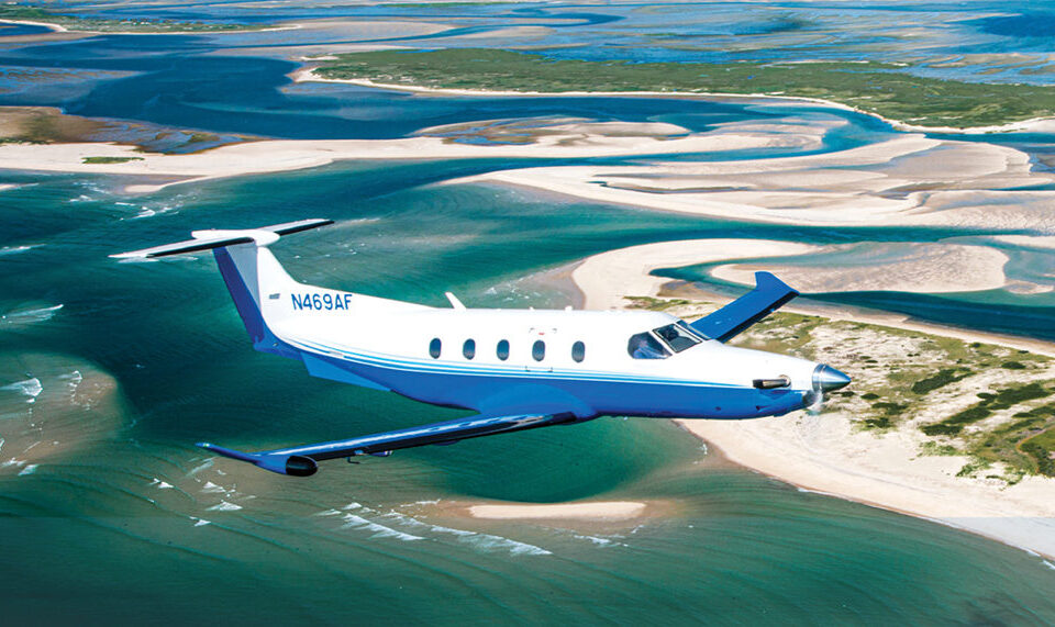 PC-12 flying over a beach